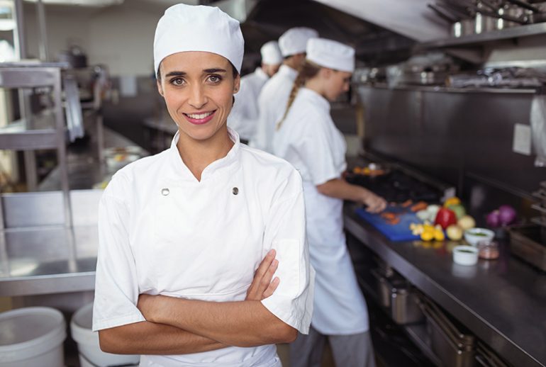 Portrait of kitchen staff standing with arms crossed in commercial kitchen